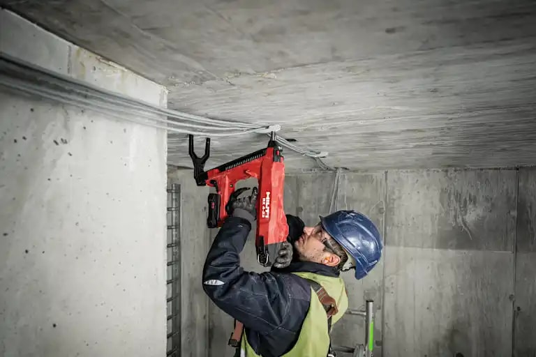 Profesional utilizando la clavadora a batería Hilti BX 4-22 en obra para aplicaciones de fijación de cables en hormigón