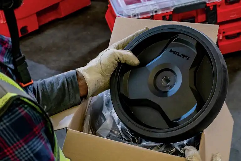 Een man houdt een reservewiel van de ProKit terwijl de ProKit op de achtergrond staat