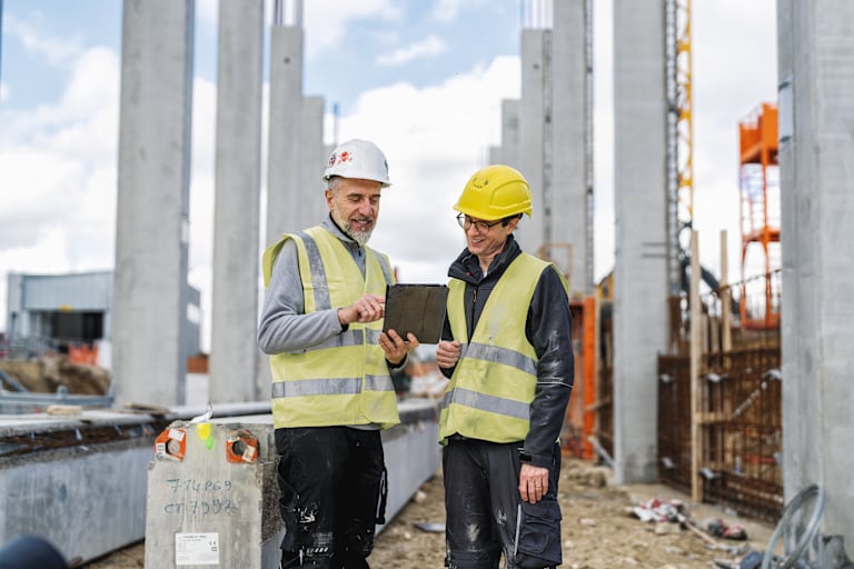 Ouvriers sur chantier examinant des plans de construction