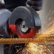 Persoon gebruikt een Hilti-haakse slijper om een metalen staaf te snijden, met vonken die wegspatten