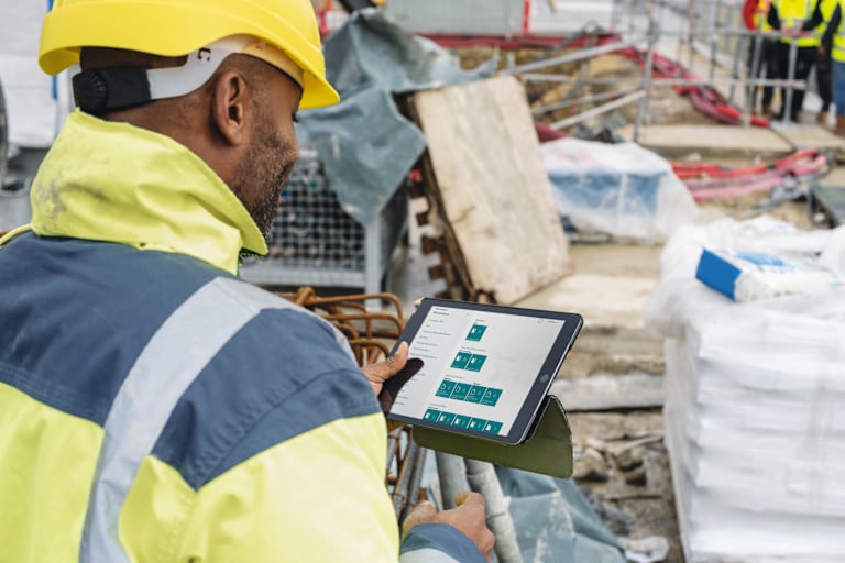 Une tablette affichant Fieldwire sur une table avec plan de construction