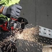 Persoon gebruikt een Hilti-haakse slijper om een metalen staaf te snijden, met vonken die wegspatten