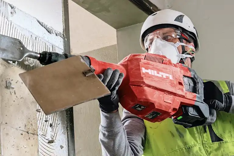 Arbeiter mit Hilti Meißelhammer mit Spatmeißel beim Fliesenabschlagen von einer Wand