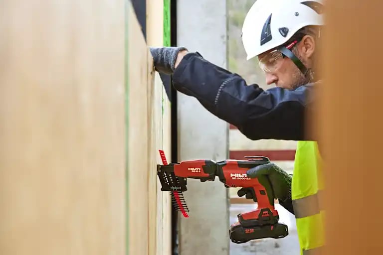 A worker using the SD 5000-22 with B22-85 battery and magazine SD-M 2 to mount an OSB plate