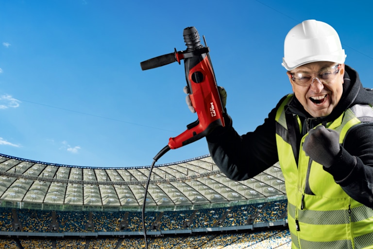 Visual showing a man cheering at a football stadium with a Hilti tool in his hand