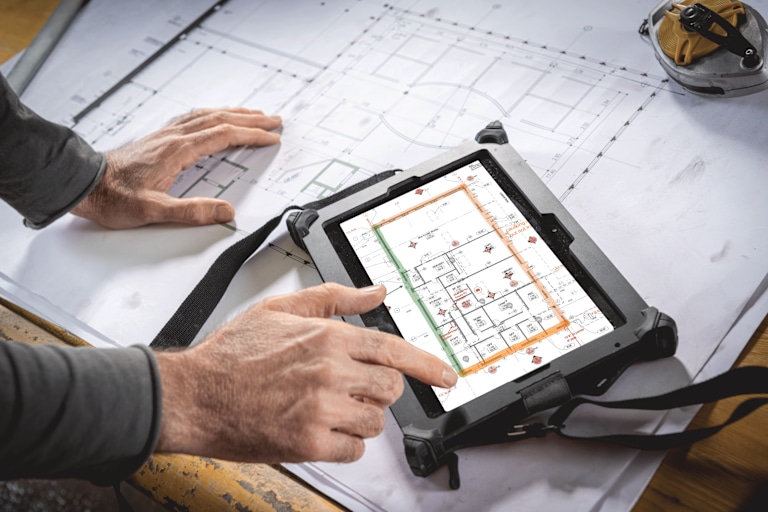 Une tablette affichant Fieldwire sur une table avec plan de construction
