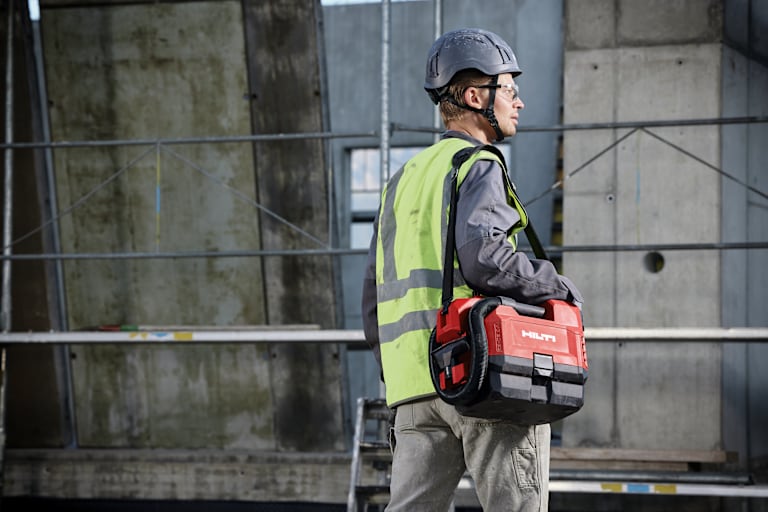 Un client porte un aspirateur Hilti sur un chantier