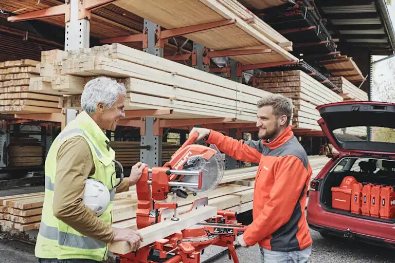 Mood image of Sales person/TS showing customer the SM 60-22 Miter Saw. The two people are on a mass timber/wood construction site.
