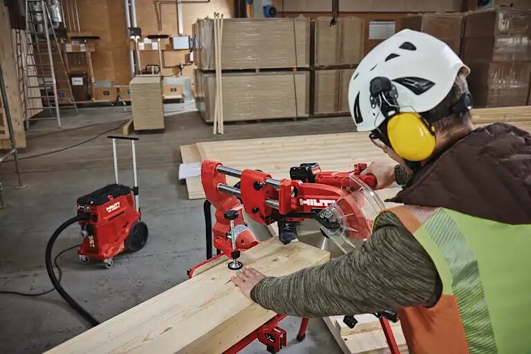 Application picture of the cordless miter saw SM 60-22 attached to the cordless vacuum cleaner VC 4X-22. Wood cutting application. Application without gloves.