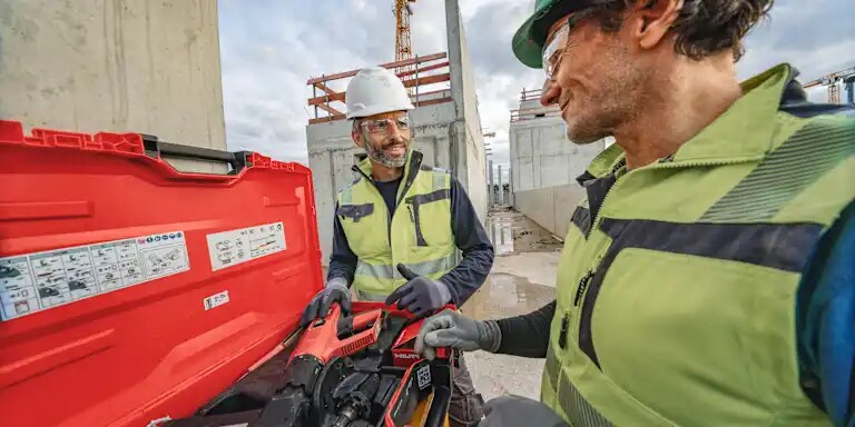 Two male workers on a jobsite, checking Hilti direct fastening tool