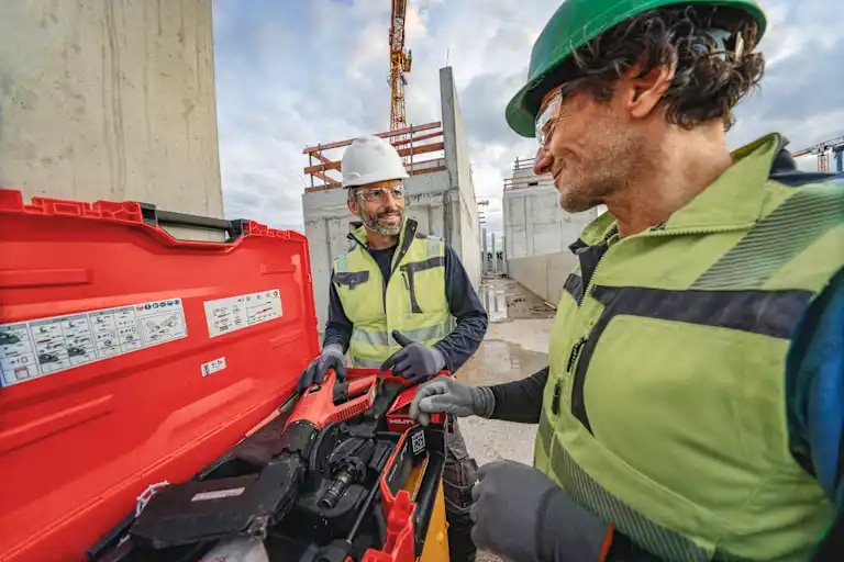 Two male workers on a jobsite, checking Hilti direct fastening tool