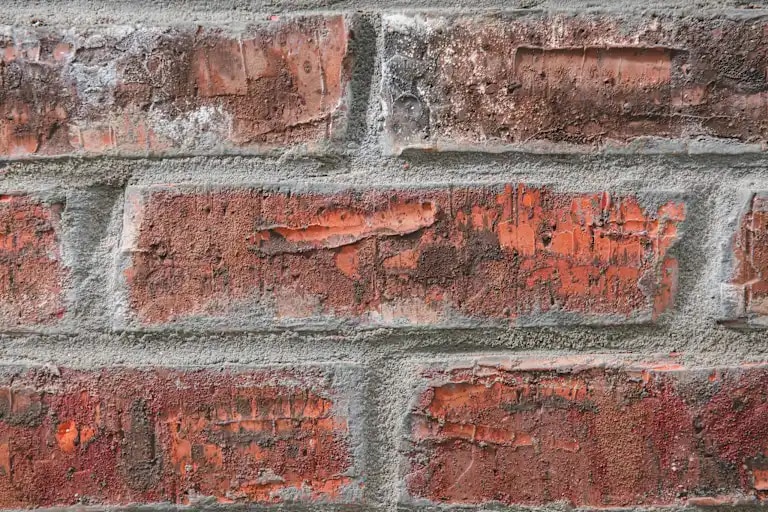 Eine rote Ziegelmauer mit gleichmäßigem Mauerwerksverband und sichtbaren Mörtelfugen.