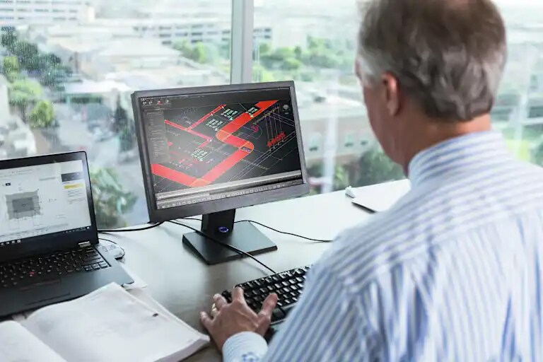 Um homem a utilizar o Seletor de Proteção Contra Incêndios da Hilti no seu computador de secretária