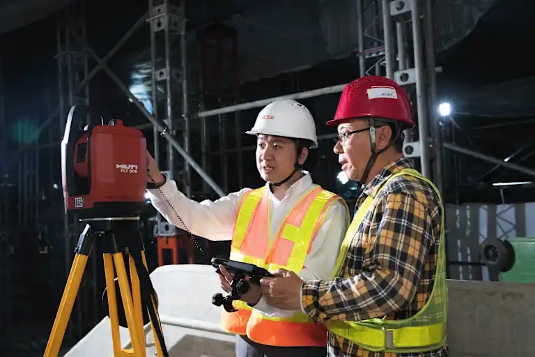 Asian Account Manager consulting with customer on jobsite holding tablet and showing a PLT 300 Digital Layout laser tool