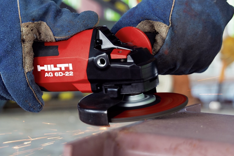 Persoon gebruikt een Hilti-haakse slijper om metaal te slijpen, met vonken die wegspatten