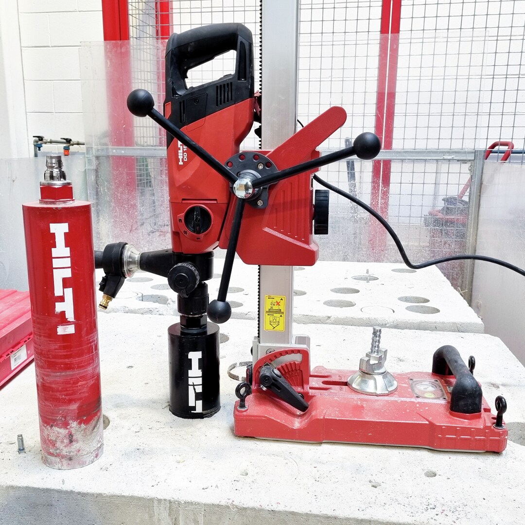 Image of the diamond coring tool DD-150 with core bits with a jobsite background for social media.