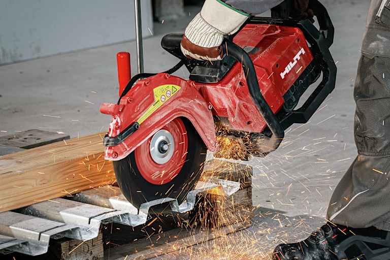 Personne utilisant une découpeuse Hilti pour couper un tube de métal