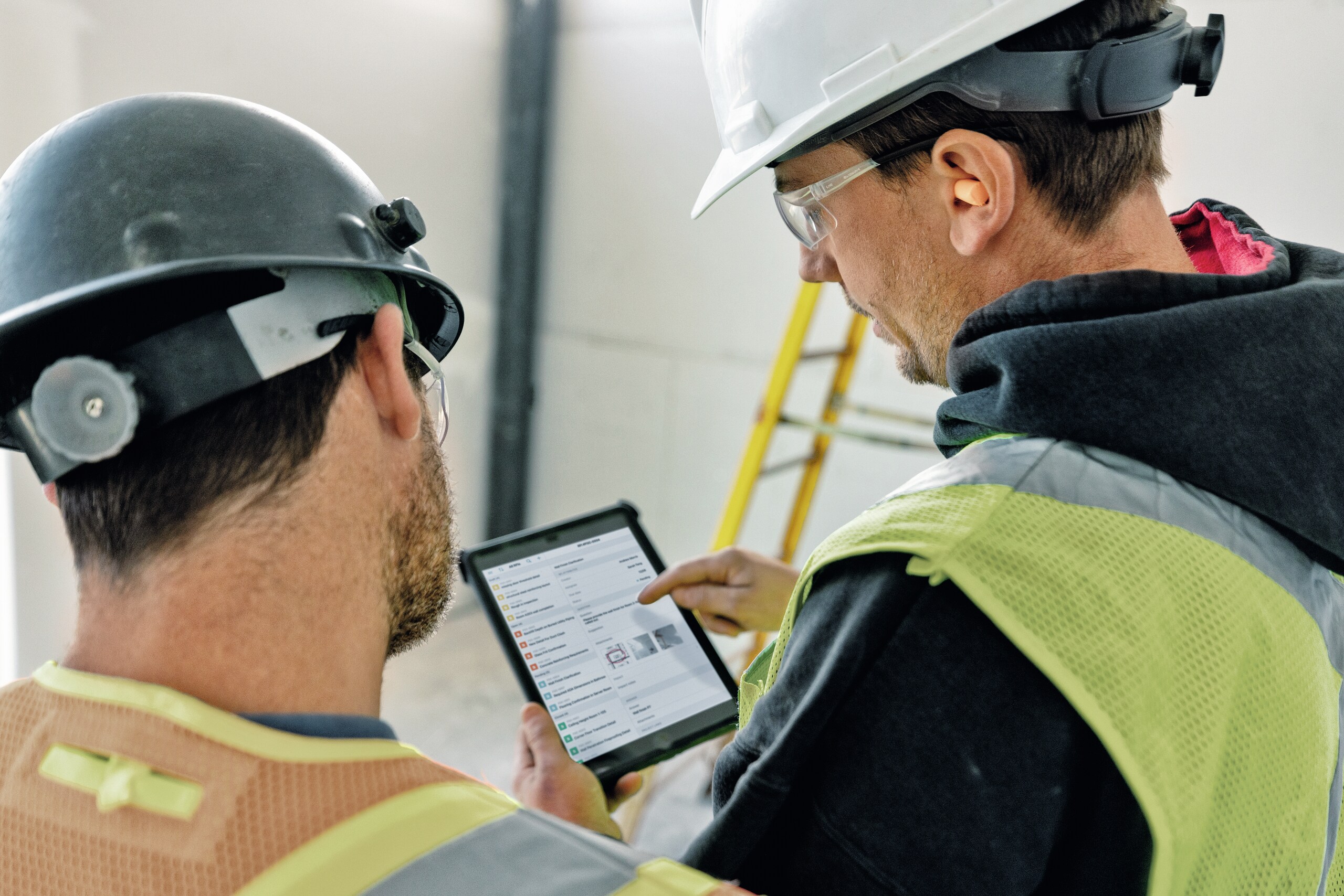 Responsable des opérations et ouvrier sur chantier utilisant une tablette avec Fieldwire