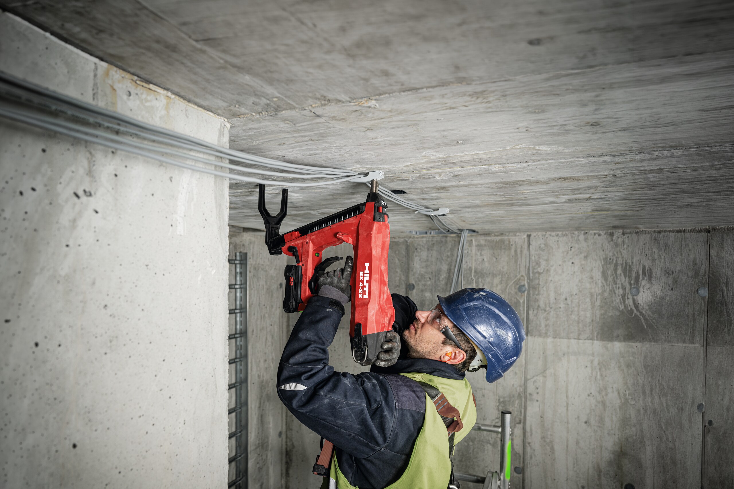 Profesional utilizando la clavadora a batería Hilti BX 4-22 en obra para aplicaciones de fijación de cables en hormigón