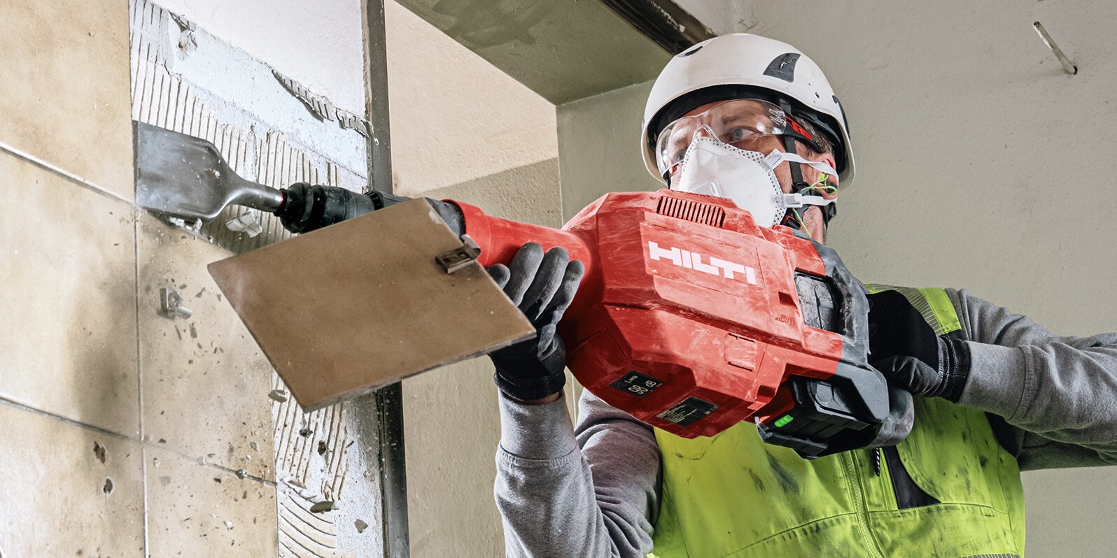 Arbeiter mit Hilti Meißelhammer mit Spatmeißel beim Fliesenabschlagen von einer Wand