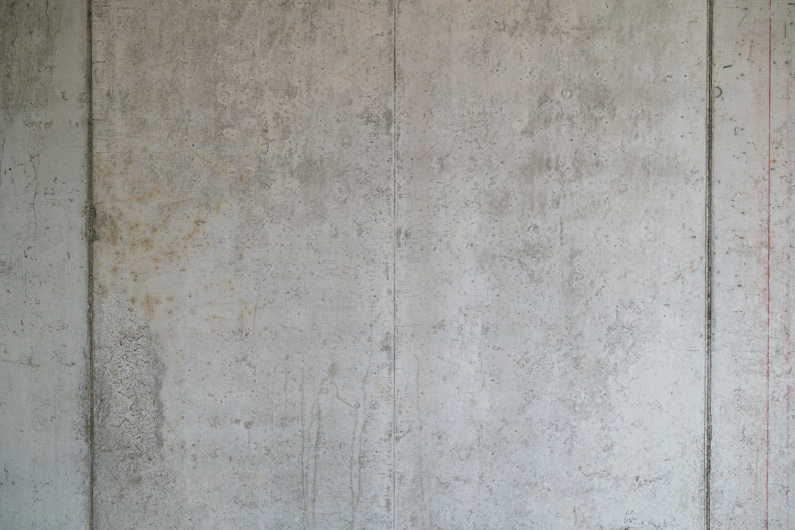 Eine Betonwand mit glatter grauer Oberfläche und sichtbaren vertikalen Fugen zwischen den Betonsegmenten.