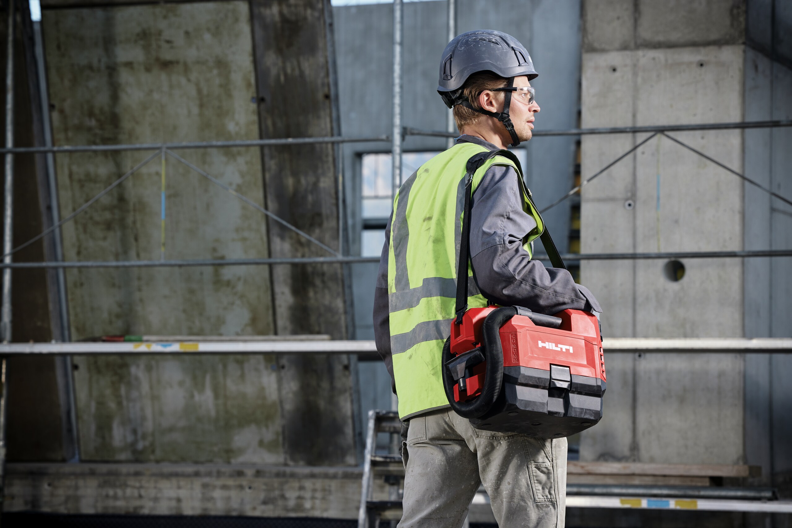 Un client porte un aspirateur Hilti sur un chantier