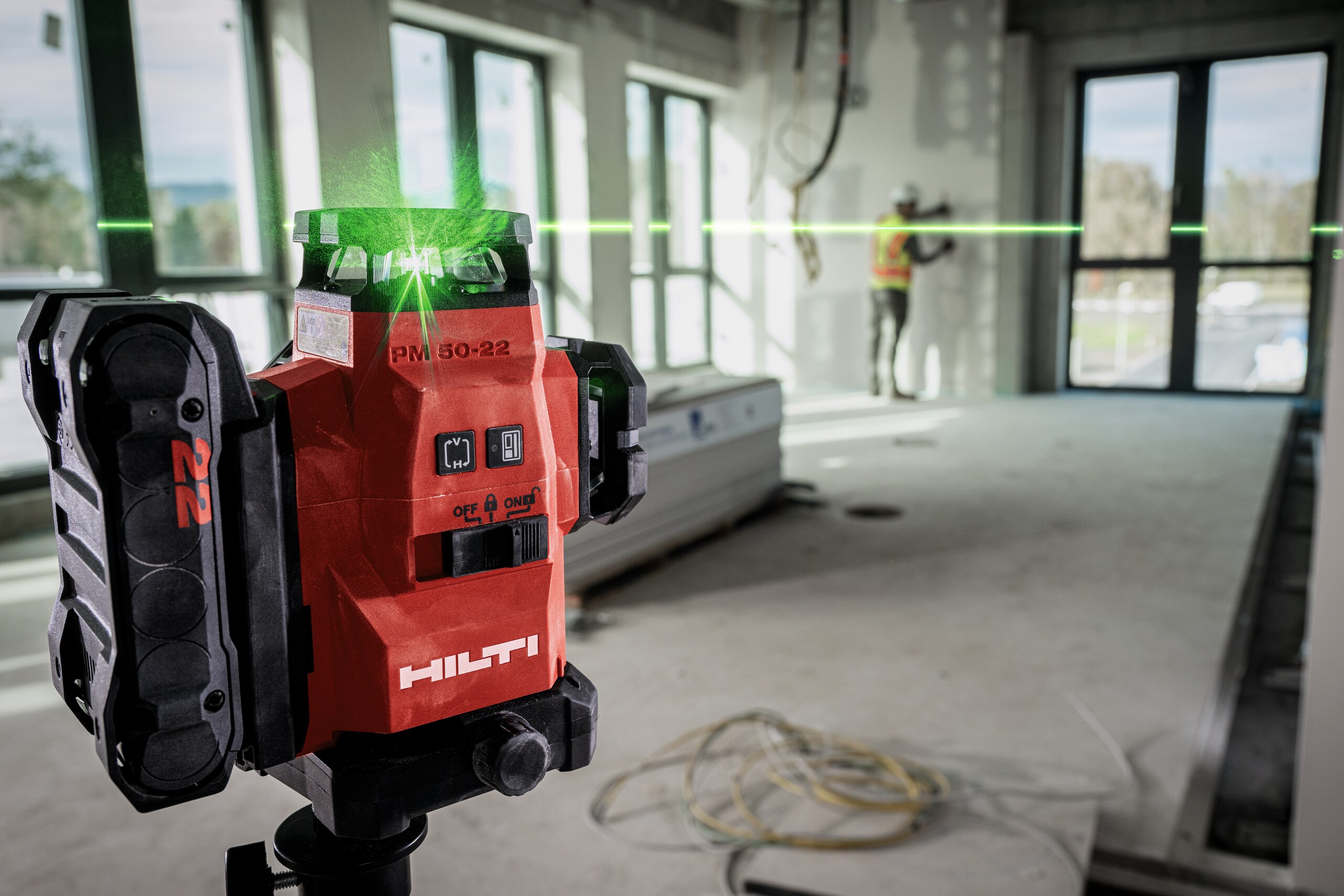Rode Hilti-laserwaterpas projecteert groene laserlijn in een onafgewerkte ruimte