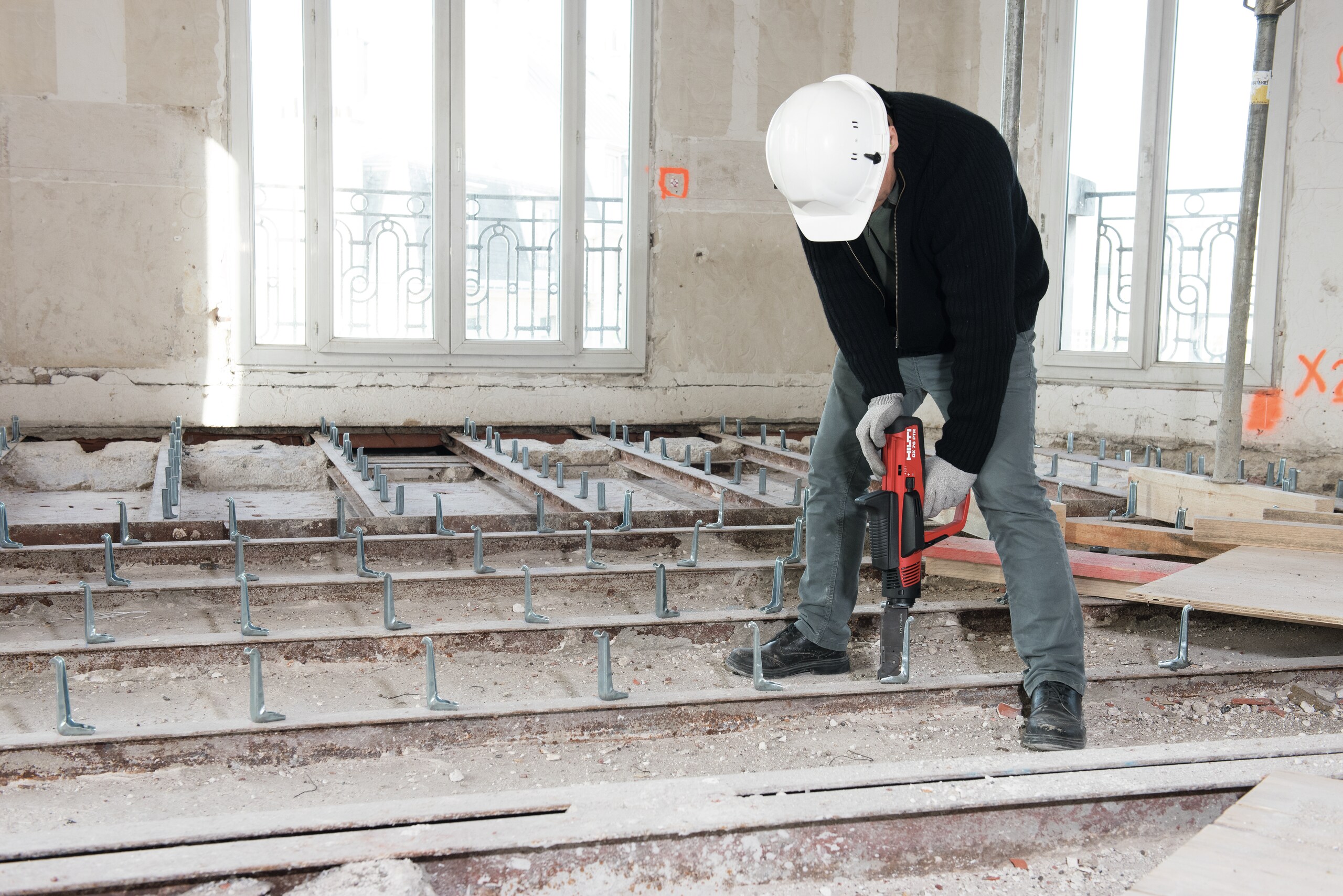 Ouvrier métallier fixant des attaches à l'aide d'un cloueur