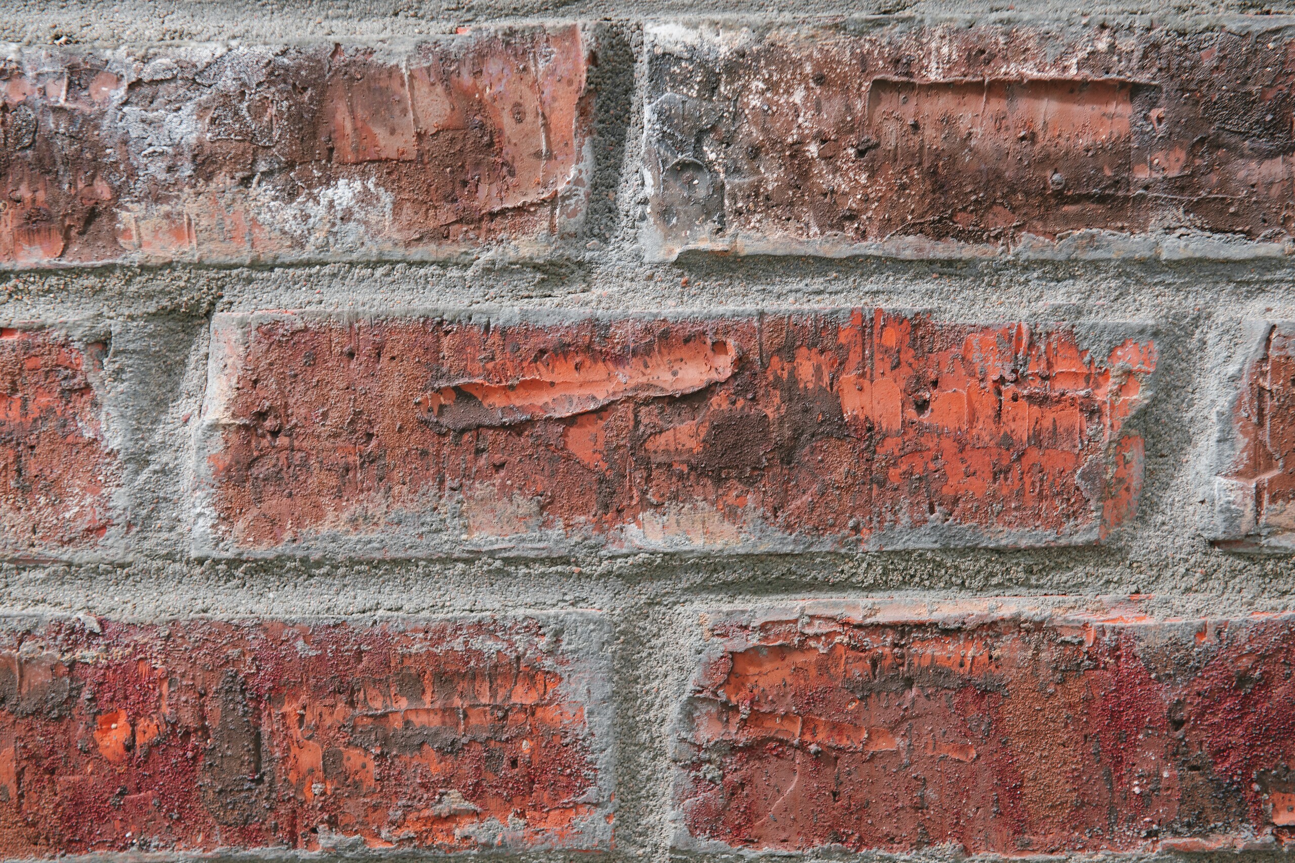 Eine rote Ziegelmauer mit gleichmäßigem Mauerwerksverband und sichtbaren Mörtelfugen.
