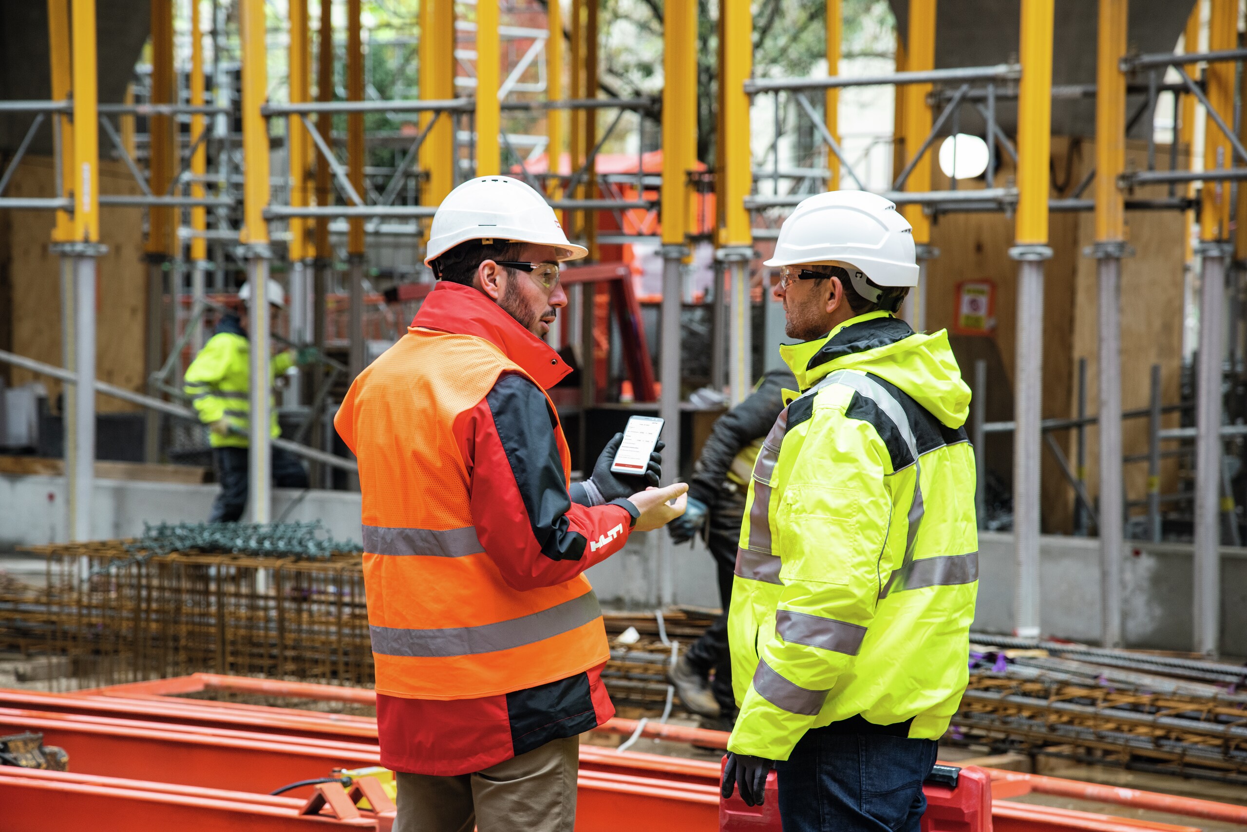 Construction professional and account manager using software on jobsite.