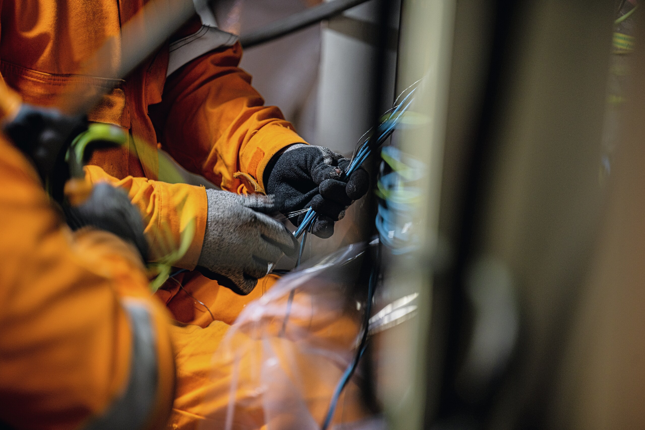 The hands of an electrician working on some cables or electrical wires.